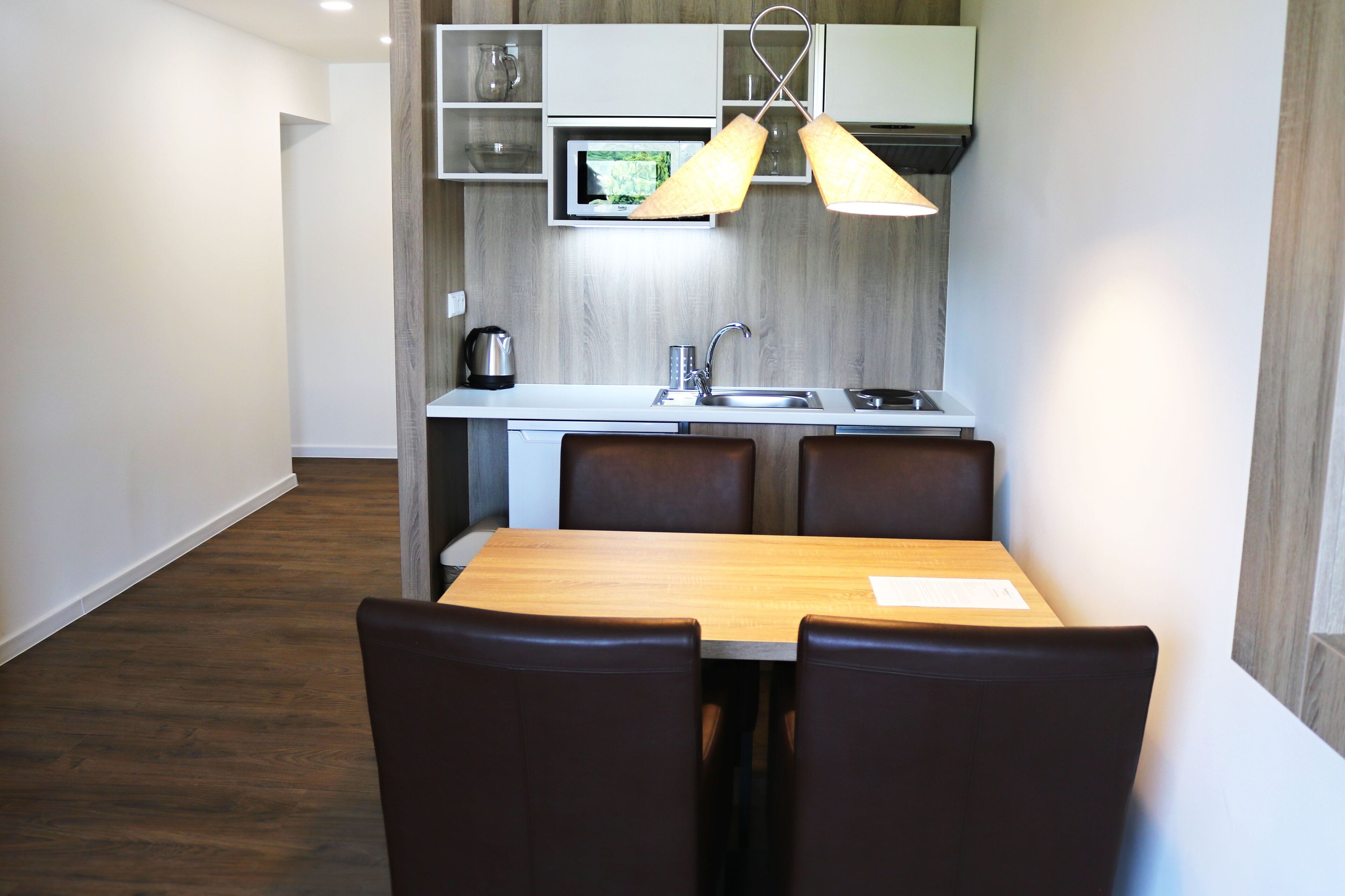 A compact kitchen with a microwave, sink, and two pendant lights.