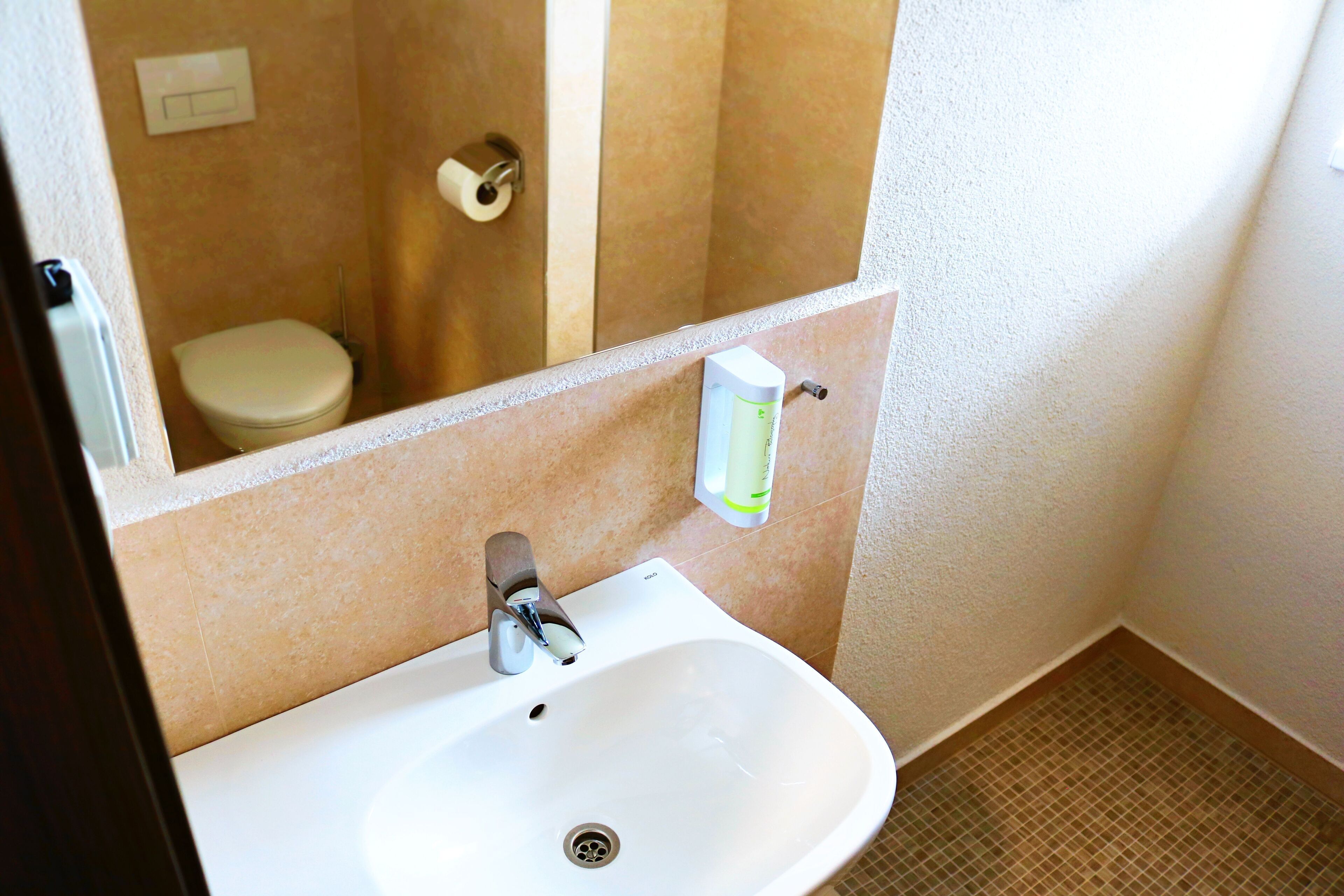 A bathroom with a white sink, a mirror, a toilet, and a shower area.