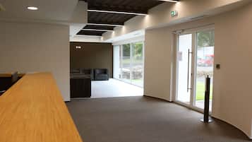 Ein moderner Arbeitsraum mit einem langen Holztisch, einer Sitzecke mit Stühlen und einer großen Glasdoor, die nach draußen führt.