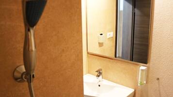 A bathroom with a shower, sink, and mirror.