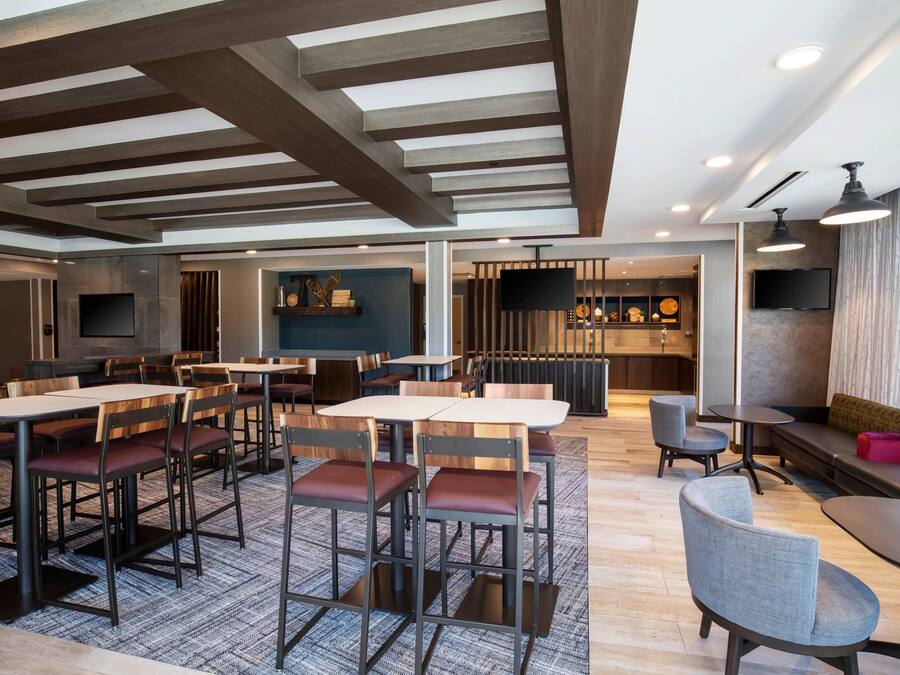 A modern restaurant with wooden tables and chairs, a bar area, and a seating area with a view.