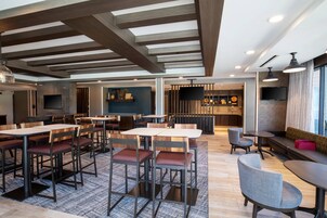 Um restaurante moderno com mesas e cadeiras de madeira, um espaço de bar e uma área de estar com vista.