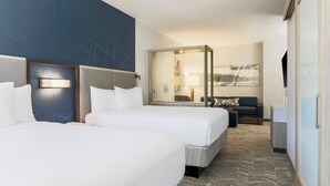 Ein Hotelzimmer mit zwei Betten, einem großen Spiegel, einem Sofa und einem Fernseher.