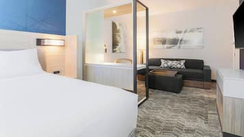 A hotel room with a bed, a desk, a sofa, and a mirror.