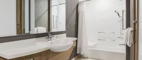 A modern bathroom with a large sink, mirror, and shower area.