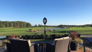 A patio with wicker furniture and a clock, overlooking a golf course and a lake. - 4-bedroom 4.5 bath Home in Bear Trap Golf Resort-- 3 minutes from Bethany Beach (Ocean View)