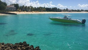 Een boot genaamd 'SMILEY' op helder turquoise water, met een strand en palmbomen op de achtergrond.