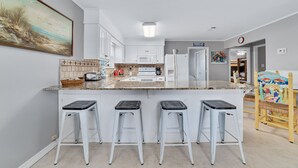 A modern kitchen with white cabinets, a granite countertop, and a central island with bar stools. - PRIVATE HOME, CLOSE TO THE BEACH, GREAT FOR FAMILIES, CONVENIENT TO EVERYTHING (Gulf Shores)
