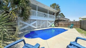A backyard with a swimming pool, a wooden deck, and a covered patio area. - PRIVATE HOME, CLOSE TO THE BEACH, GREAT FOR FAMILIES, CONVENIENT TO EVERYTHING (Gulf Shores)