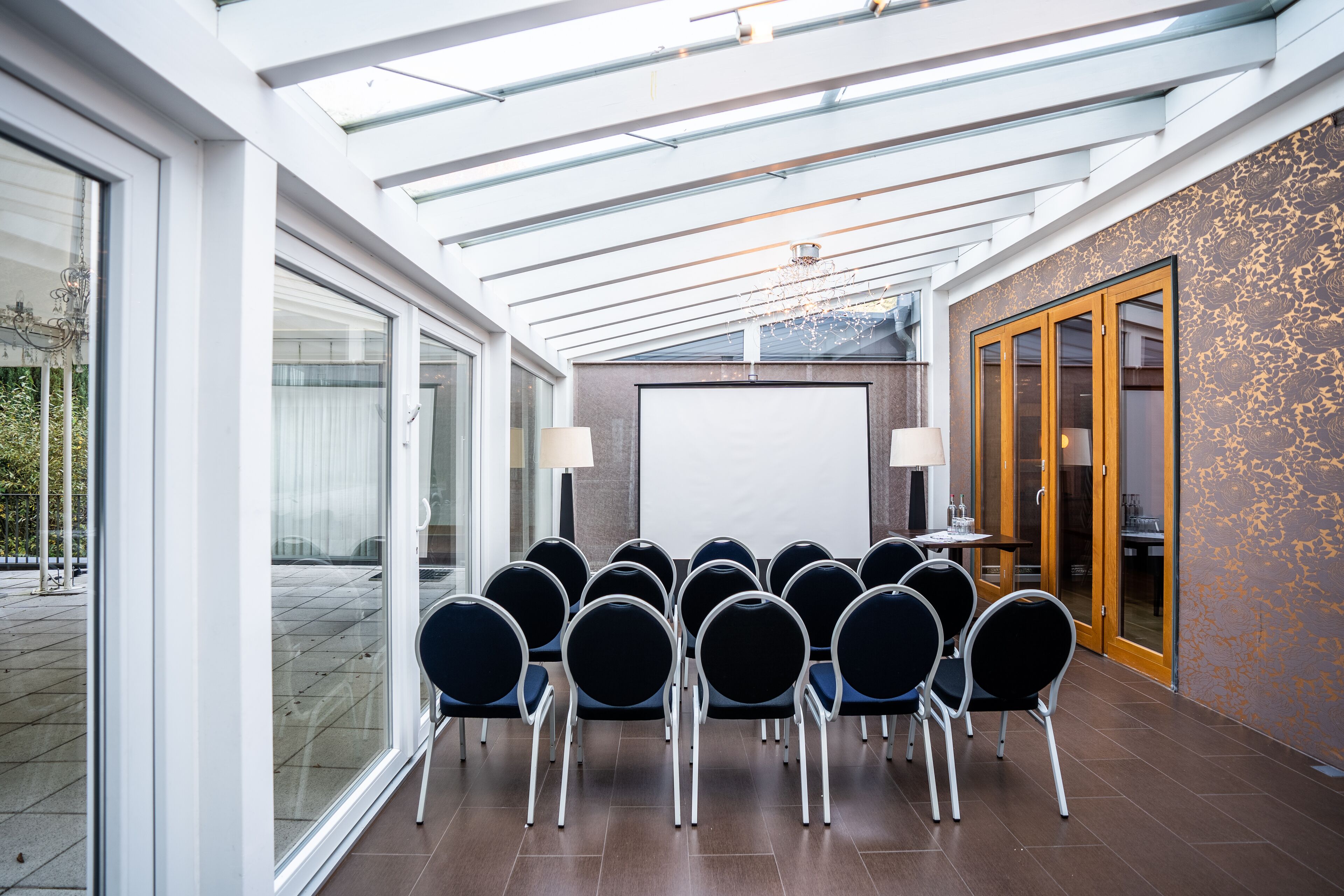 A conference room with a glass ceiling, a whiteboard, and a row of chairs.