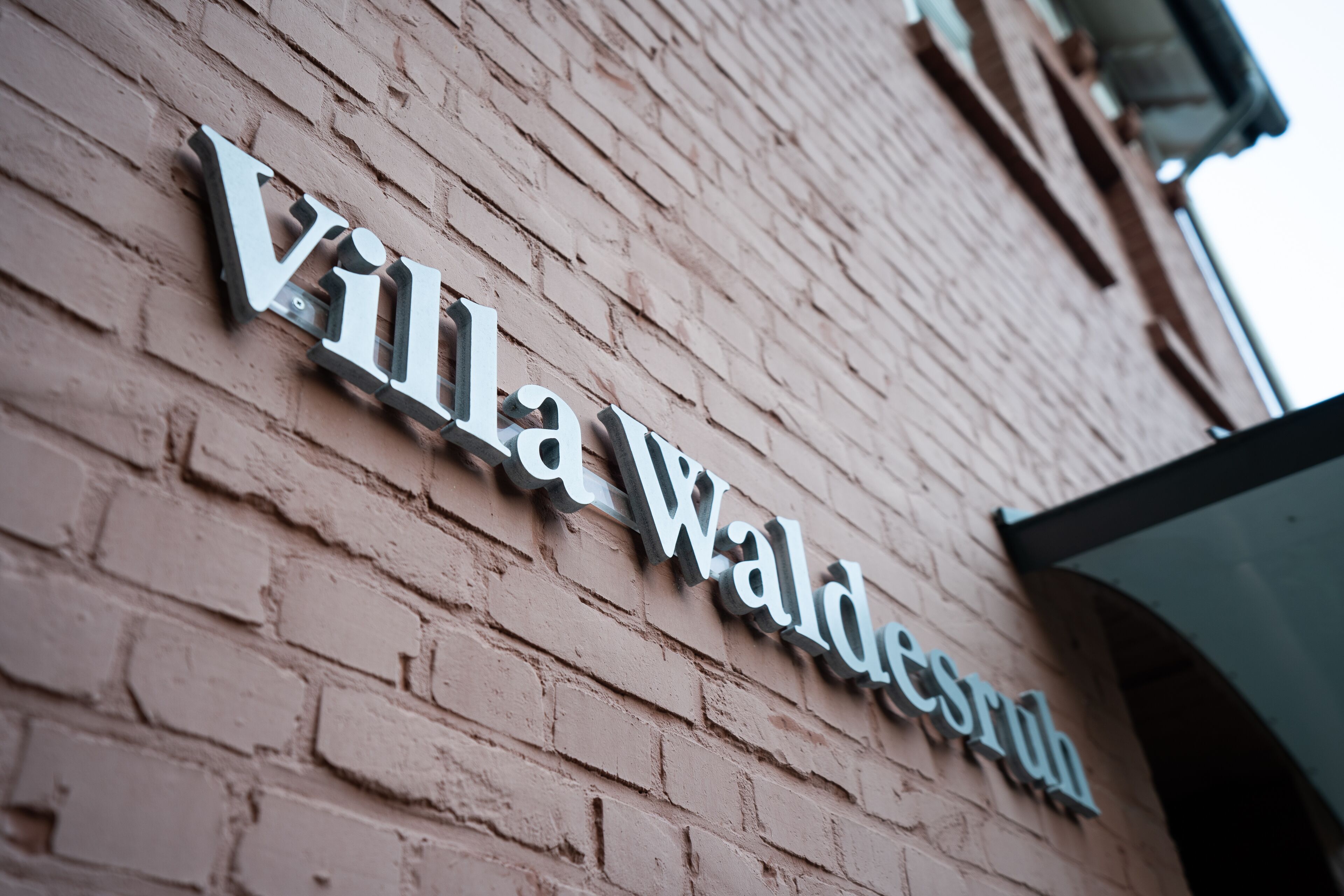 A sign for Villa Waldensburg on a brick wall.