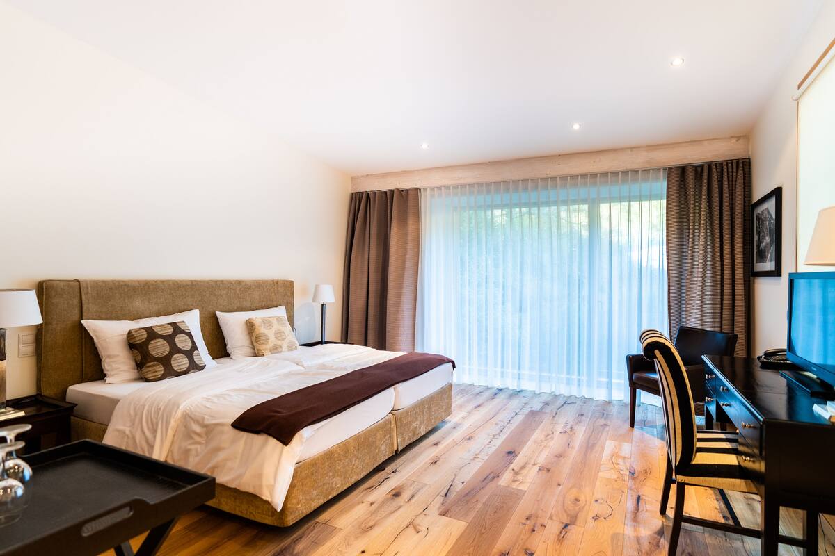 A hotel room with a large bed, a desk, and a television.
