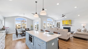 A spacious kitchen with a large island, wooden cabinets, and a dining area with chairs and a table. - NEW LUXURY HOME, 2 houses from BEACH,5 Bedroom,Sleeps 12,Heated POOL, Game Room (Long Beach Township)