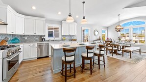 A spacious kitchen with white cabinets, a large island, and wooden chairs. - NEW LUXURY HOME, 2 houses from BEACH,5 Bedroom,Sleeps 12,Heated POOL, Game Room (Long Beach Township)