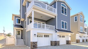 A multi-story residential building with a front porch, a garage, and a balcony. - NEW LUXURY HOME, 2 houses from BEACH,5 Bedroom,Sleeps 12,Heated POOL, Game Room (Long Beach Township)