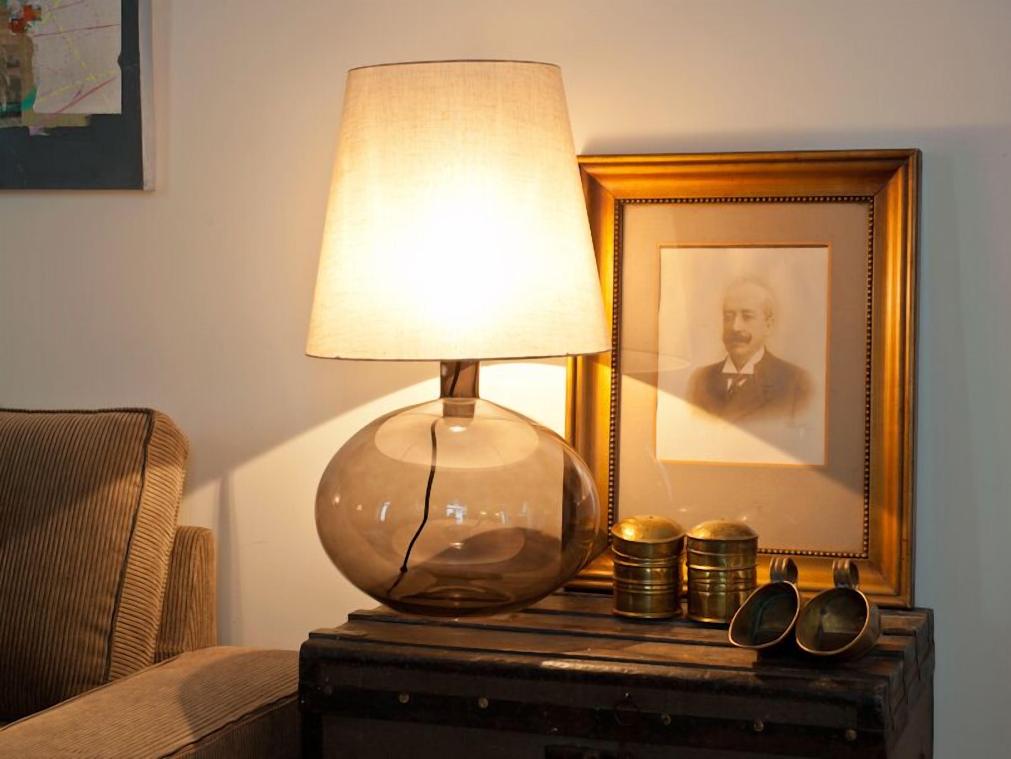 A lamp, a framed portrait, and brass containers on a wooden table.