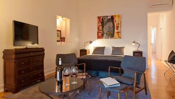 A modern bedroom with a bed, bedside tables, a TV, a coffee table, and seating area.