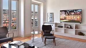 A modern living room with a large window, a flat-screen TV, and a comfortable seating area. - Casa Balthazar (Lisbon)
