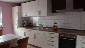 A modern kitchen with white cabinets, a stainless steel sink, and a built-in oven. - Vacation apartment Haus am Jakobsweg (Fischbach bei Dahn)