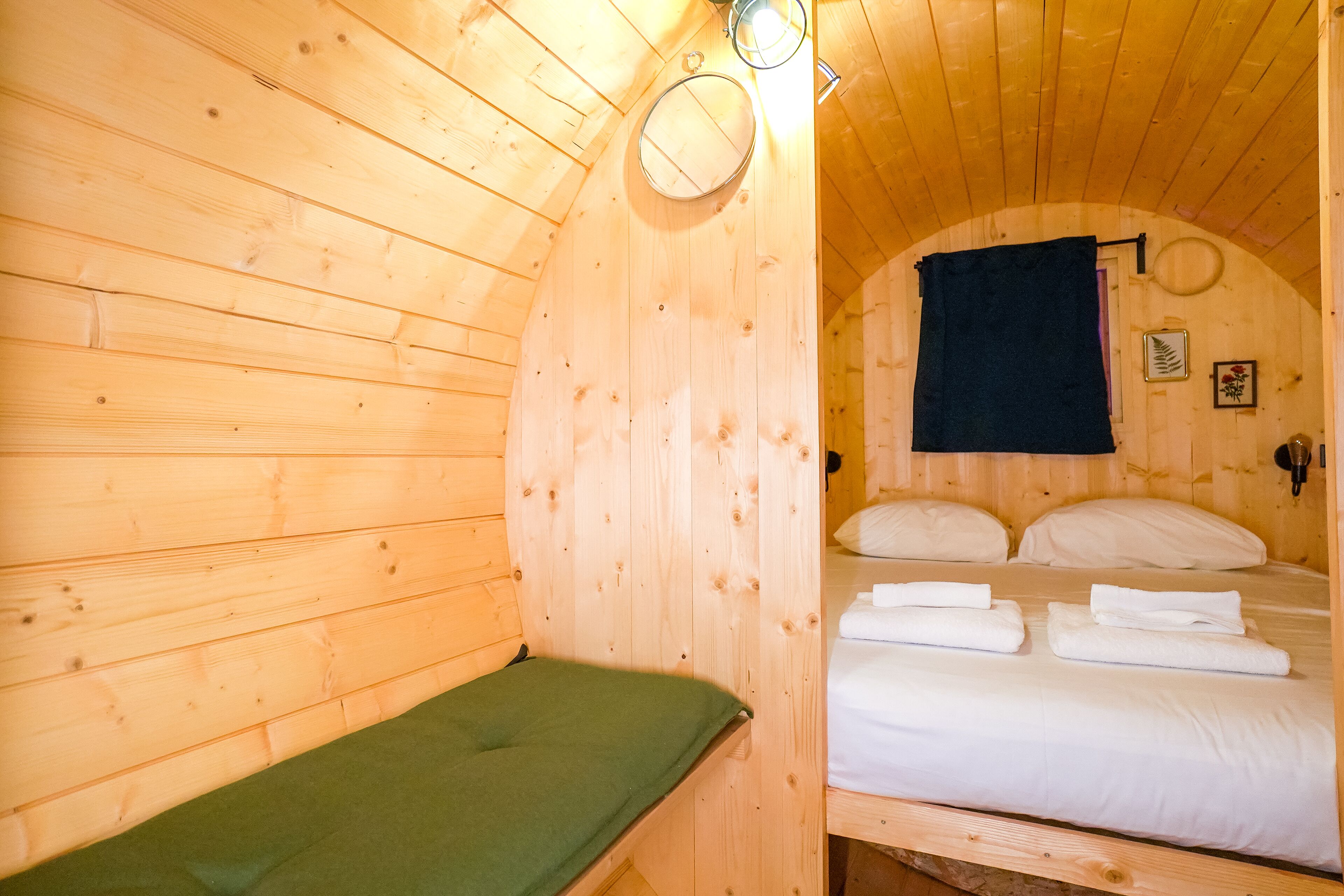 A wooden cabin room with a single bed, a bench, and a small table.
