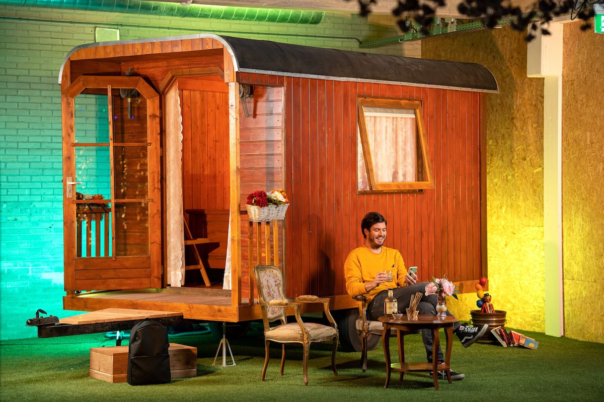 A wooden cabin with a porch, a chair, a table, and a small garden area.