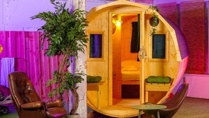 A cozy wooden cabin with a single bed, a potted plant, and a leather chair. - Outside Inn (Amsterdam-Duivendrecht)