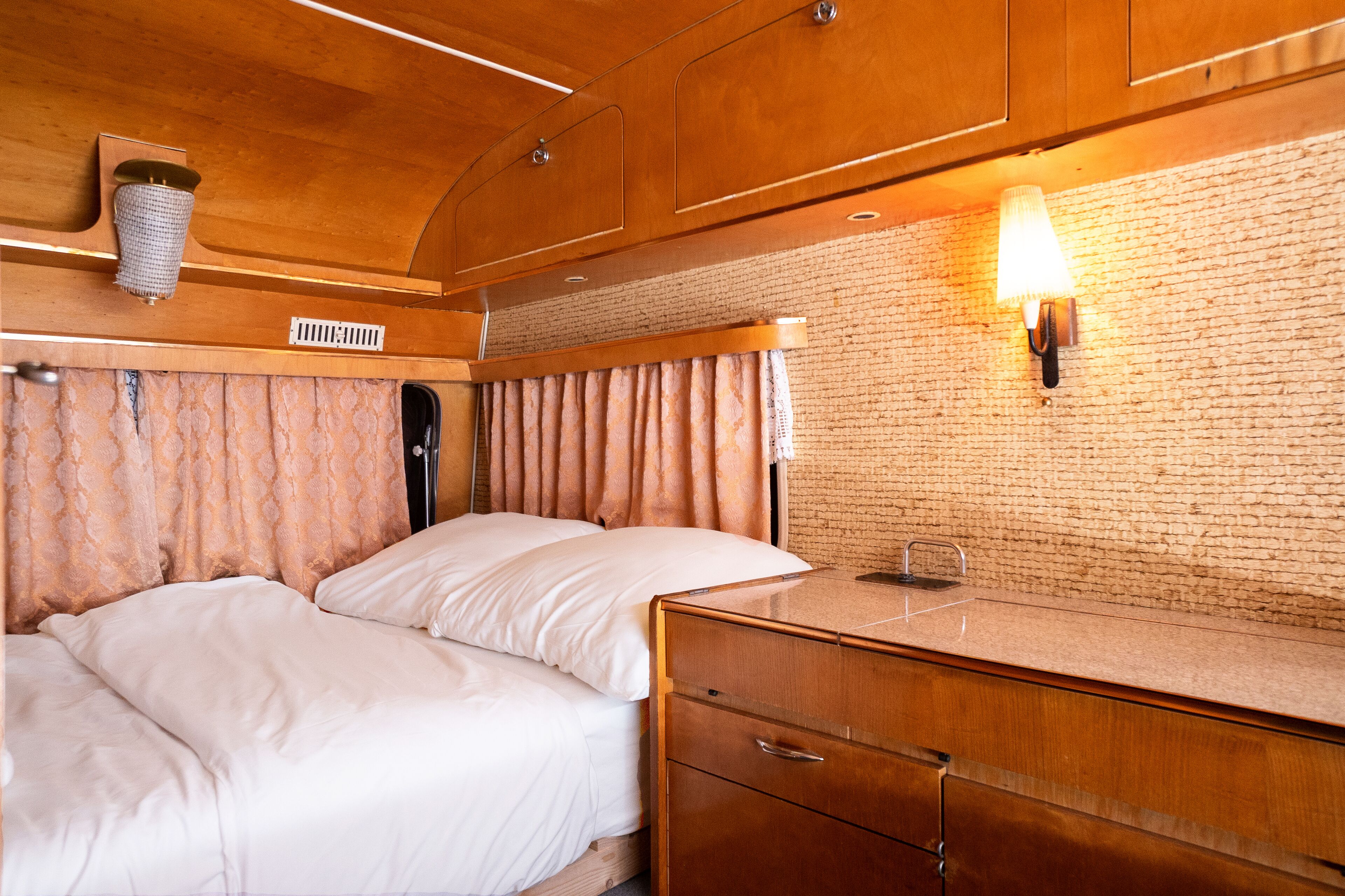 Une chambre à coucher avec un lit, des armoires en bois et un mur en briques.