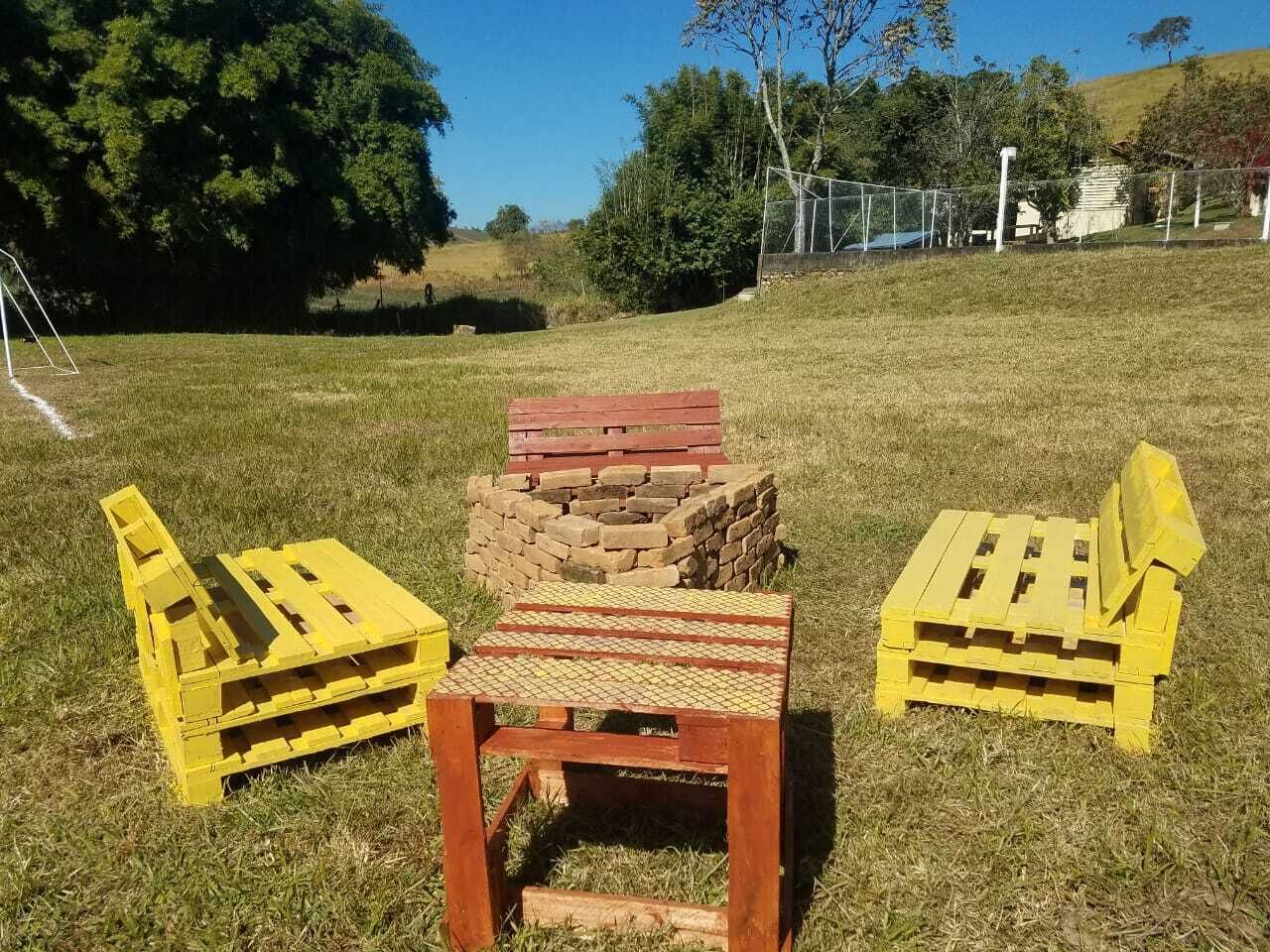 Un espacio de estar al aire libre rústico con una mesa de madera y dos sillas amarillas.