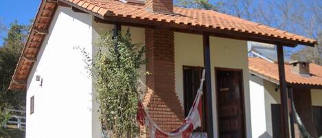 A single-story building with a red-tiled roof, a brick chimney, and a white exterior wall.