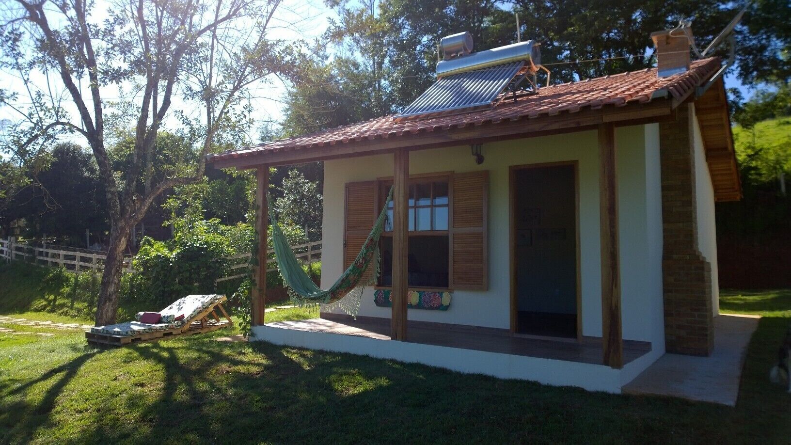 A small house with a tiled roof, a hammock, and a patio area.