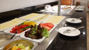 Un bufé con diversas opciones de comida, incluyendo frutas, verduras y ensaladas.