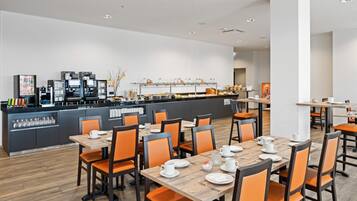 Un'area ristorazione moderna con diversi tavoli e sedie, un angolo caffè e un buffet.