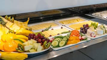 Un bufé con diversas frutas, quesos y otros productos.