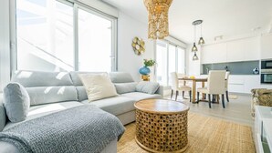 Ein modernes Wohnzimmer mit einer Couch, einem runden Couchtisch und einem Essbereich mit Stühlen und Tisch.