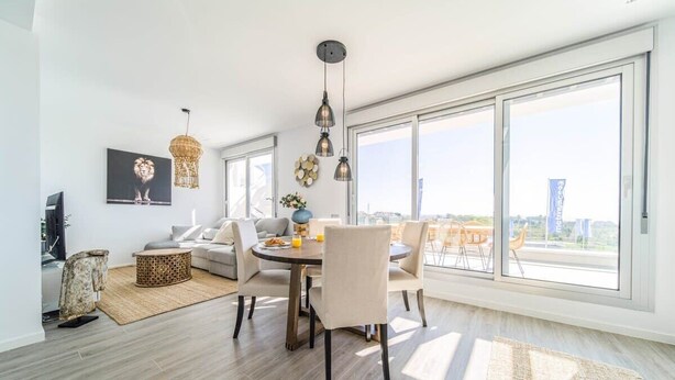 Ein modernes Wohnzimmer mit Essbereich, großen Fenstern und Blick auf die Stadt.