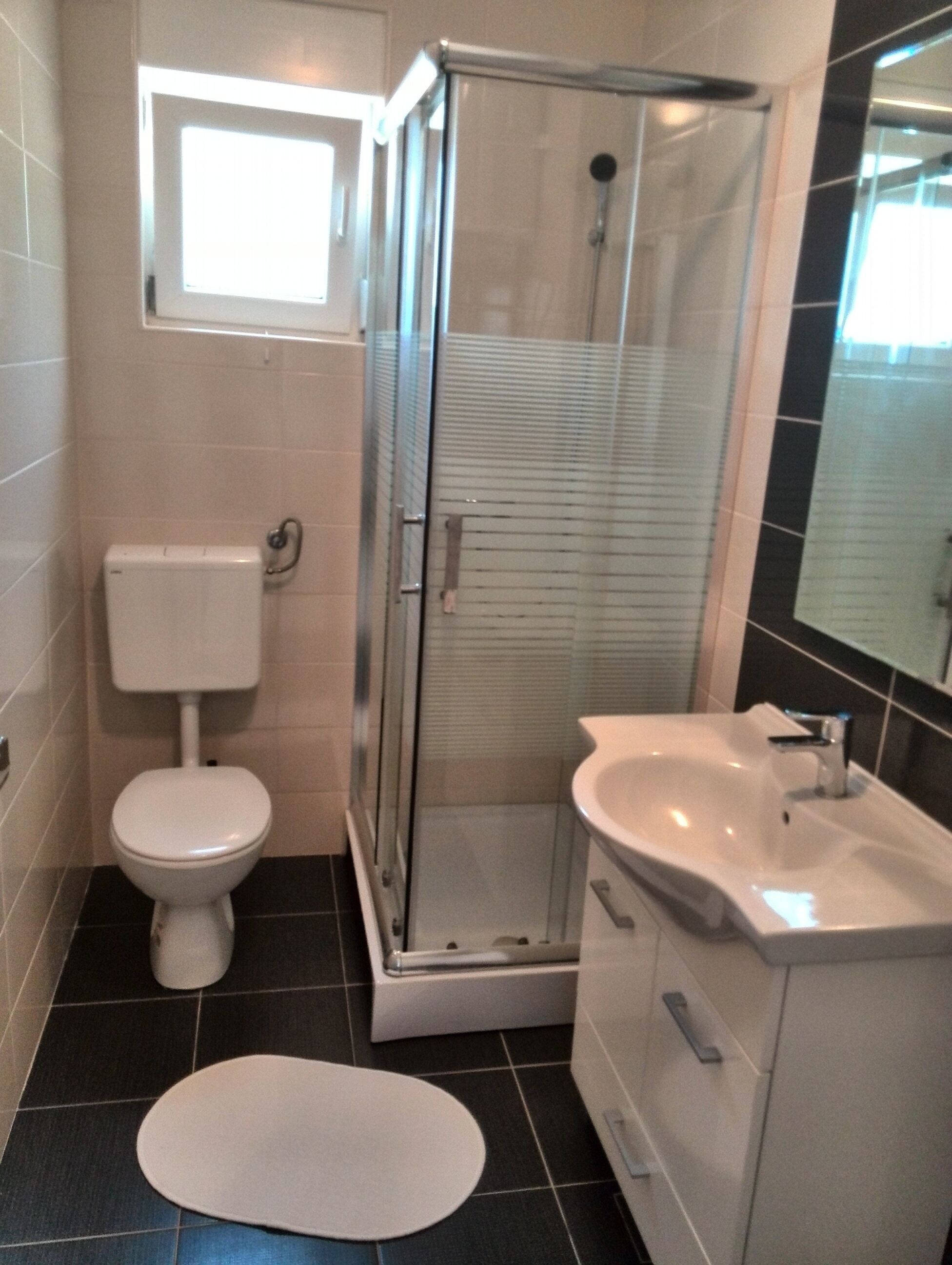A bathroom with a toilet, a shower enclosure, and a sink.