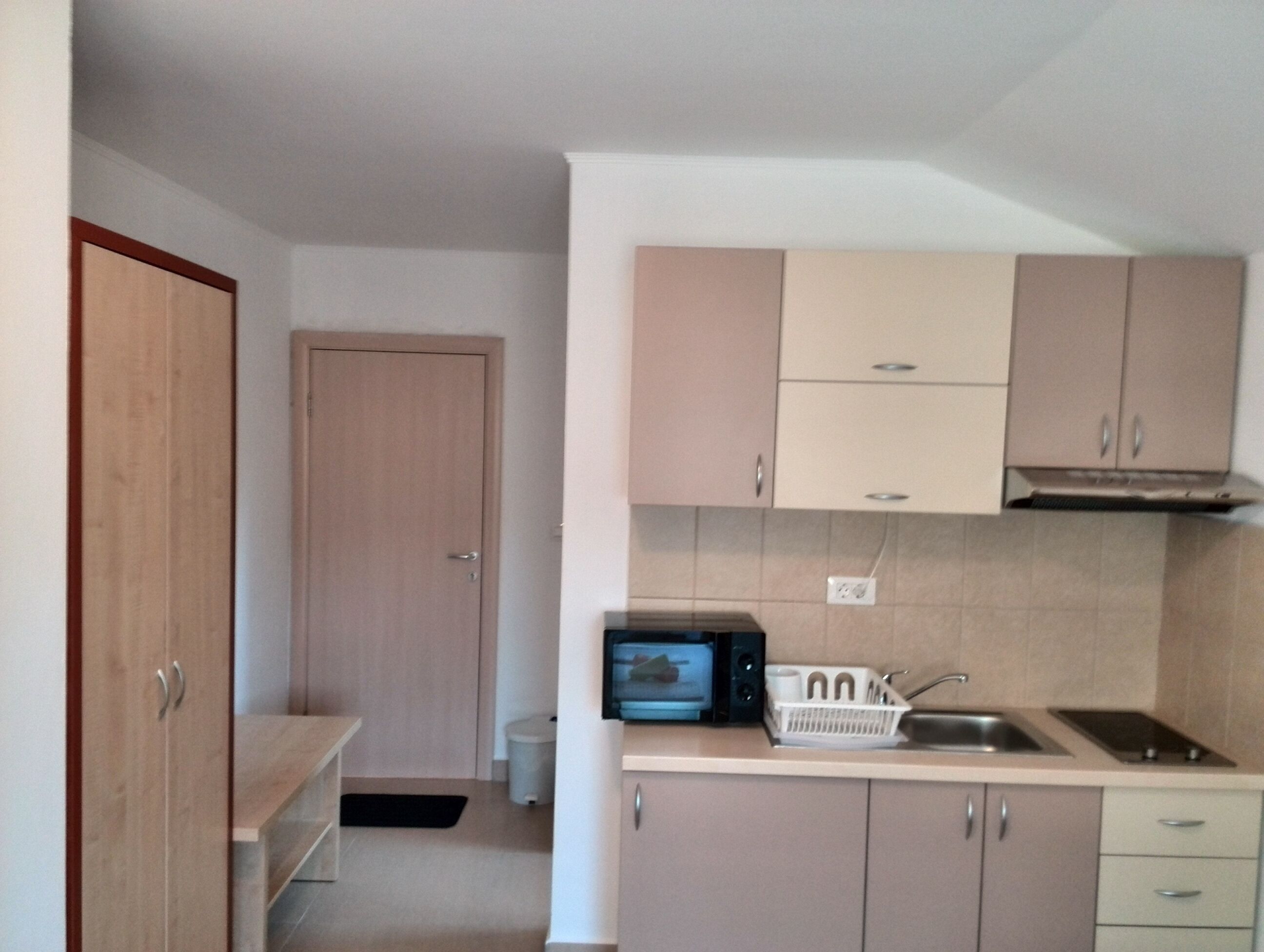 A compact kitchen with a microwave, sink, and cabinets.