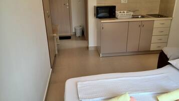 A bedroom with a bed, a bathroom with a toilet and sink, and a kitchenette with a microwave.