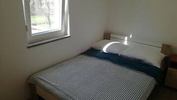 A bedroom with a bed, a window, and a nightstand.