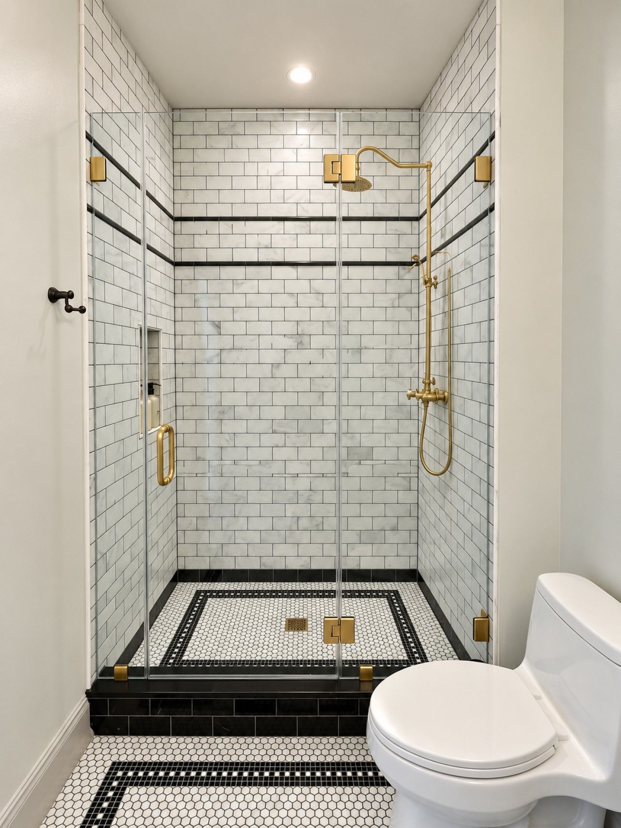 Un bagno moderno con doccia vetrata, piastrelle bianche a metro e pavimento a motivi bianchi e neri.