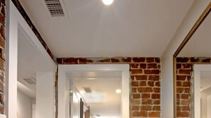 Ein Flur mit Backsteinwand, einer hölzernen Bank und einem Bett im Hintergrund.