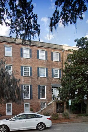 A multi-story brick building with a white car parked in front.