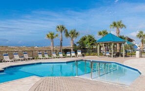 A pool area with lounge chairs, a gazebo, and palm trees. - Orange Beach Alabama, 1 Bedroom Phoenix East 22102 (Orange Beach)