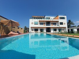 Una piscina al aire libre, sillones reclinables de piscina