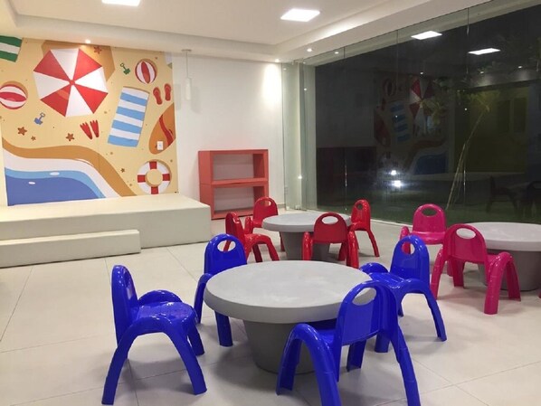 A children's play area with round tables and plastic chairs in red and blue. - 3 BEDROOM APARTMENT IN PORTO DE GALINHAS WITHIN THE RESORT (Porto de Galinhas)
