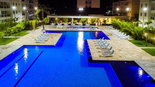 Une piscine divisée en deux zones distinctes, entourée de chaises longues et de palmiers.