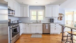 A modern kitchen with white cabinets, stainless steel appliances, and a wooden floor. - DD Ranch - Newly Renovated 10-Person Home! (Union Pier)