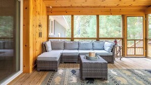 A covered porch with a sectional sofa, wicker furniture, and a patterned rug. - DD Ranch - Newly Renovated 10-Person Home! (Union Pier)