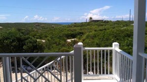 A white wooden deck with a metal railing overlooking a lush green landscape and a clear blue sky. - Cabanya Azul with view of Atlantic and small Beach within walking distance (Buckley's Settlement)