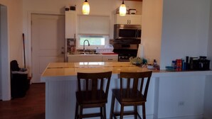 A kitchen with a central island, wooden chairs, pendant lights, and modern appliances. - Cabanya Azul with view of Atlantic and small Beach within walking distance (Buckley's Settlement)
